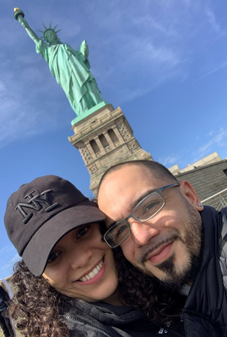 Madelin y su esposo frente a la Estatua de la Libertad