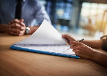 person holding pen checking documents