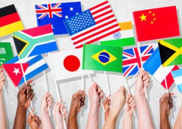 Hands holding up miniature flags of different countries