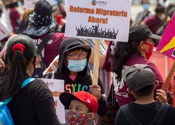 Joven en un mitin con un cartel sobre la juventud inmigrante