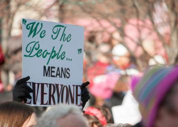 Cropped Hands Holding a sign saying We The People Means Everyone