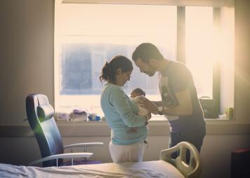 Una pareja en un hospital cargando a un recién nacido