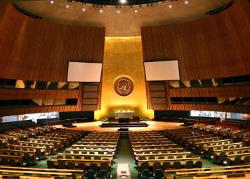 Photo of the UN General Assembly hall, a large room with gold and green colors