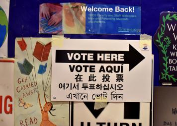 A sign in multiple languages saying "vote here"