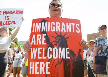 Mujer sosteniendo un cartel que dice "Immigrants Are Welcome Here"