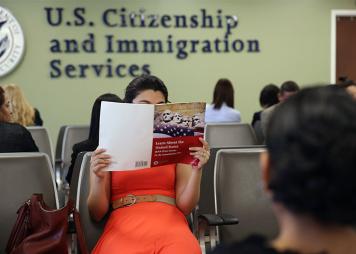 A woman holds up a US citizenship test study book 