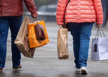 dos personas fotografiadas de espalda cargando bolsas de compras