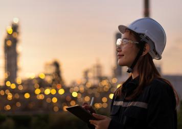 An Asian woman wearing a helmet and goggles inspects lights