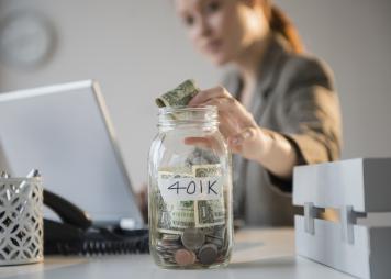 a woman puts a dollar into a glass jar with a label saying "401k" 