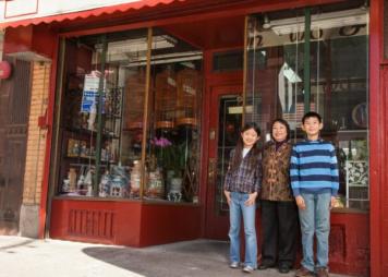 familia asiática de pie frente a la fachada de una tienda