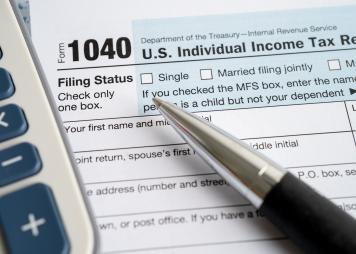 Formulario 1040 de Declaración del impuesto sobre el ingreso personal en los Estados Unidos con la bandera de EE. UU. y billetes de dólares.