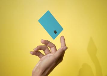 Primer plano de la mano de un hombre y de un modelo de tarjeta de crédito bancaria en el aire con servicio en línea sobre fondo amarillo