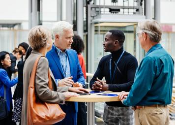 A group of business conference participants discussing a presentation in the hotel foyer together