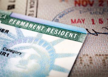 Primer plano con encuadre completo de una tarjeta de residente permanente sobre un pasaporte abierto