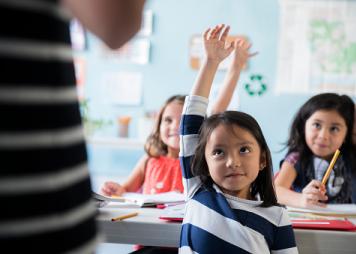 Girls raising hand for teacher in classroom