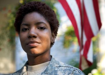 Military woman standing in front of American flag