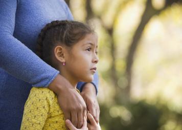 Young girl holding mothers hands