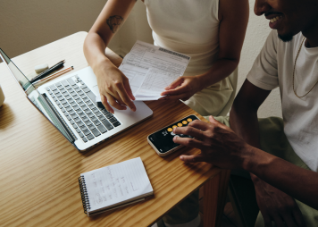 Dos personas revisan unos papeles y usan una calculadora