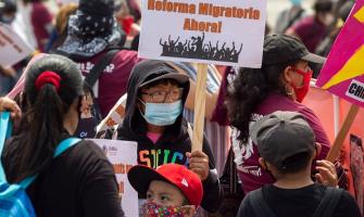 Joven en un mitin con un cartel sobre la juventud inmigrante