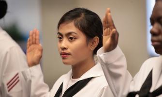 Una mujer asiática en el servicio de la marina jurando en la ceremonia de naturalización