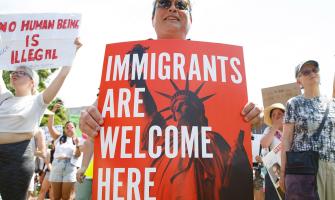 Mujer sosteniendo un cartel que dice "Immigrants Are Welcome Here"