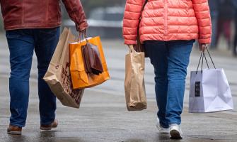dos personas fotografiadas de espalda cargando bolsas de compras