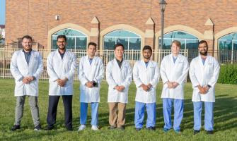 Estudiantes de medicina de la Facultad de Medicina y Ciencias de la Salud de la Universidad de North Dakota posando con su bata de laboratorio