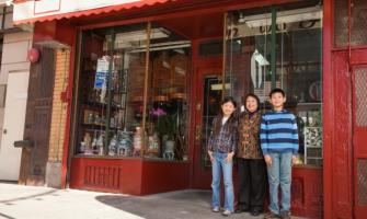 familia asiática de pie frente a la fachada de una tienda