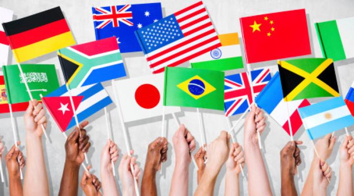 Hands holding up miniature flags of different countries