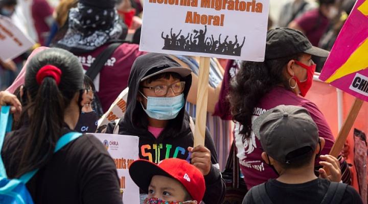 Joven en un mitin con un cartel sobre la juventud inmigrante