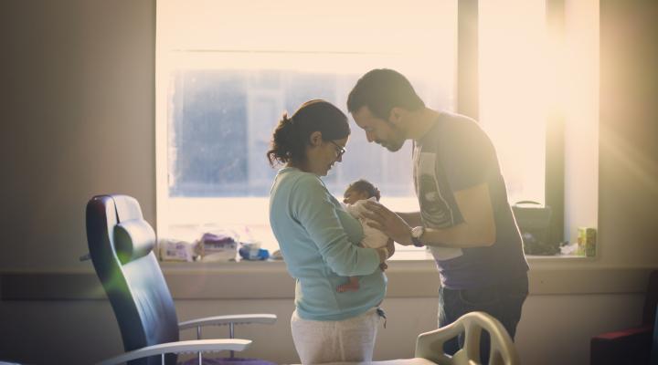 Una pareja en un hospital cargando a un recién nacido