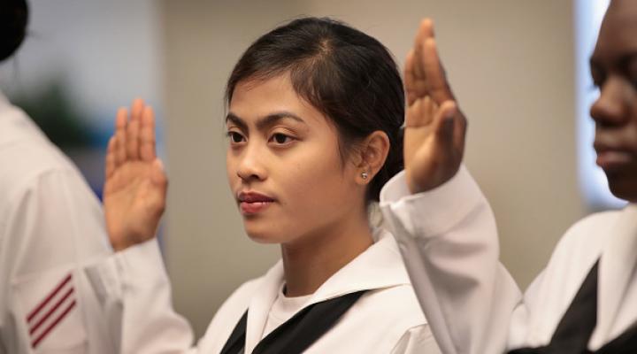 Una mujer asiática en el servicio de la marina jurando en la ceremonia de naturalización