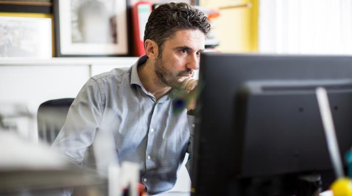 Man sitting at a desk looking at a computer 