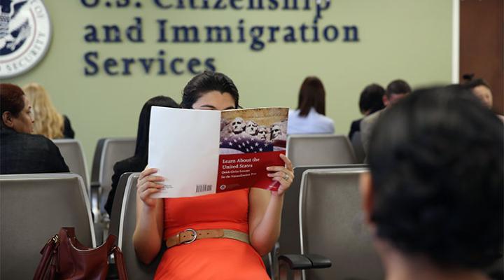 A woman holds up a US citizenship test study book 