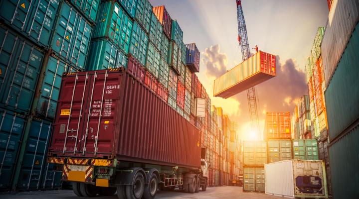 A freight truck being loaded with shipping containers