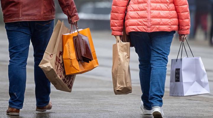 two people photographed from the back carrying shopping bags