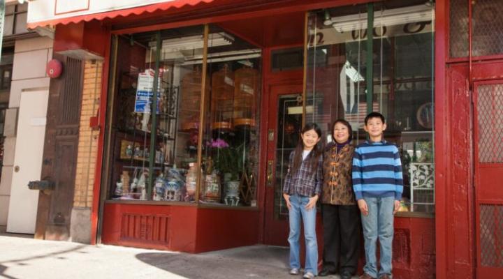familia asiática de pie frente a la fachada de una tienda