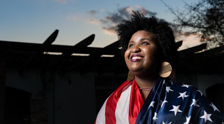 A black woman draped in the US flag smiling 