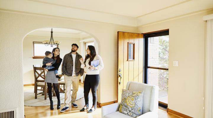 Wide shot for family with toddler in discussion with real estate agent while looking home for sale during open house