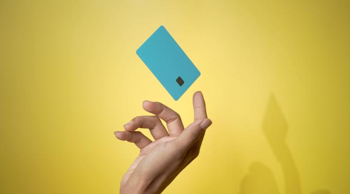 Primer plano de la mano de un hombre y de un modelo de tarjeta de crédito bancaria en el aire con servicio en línea sobre fondo amarillo