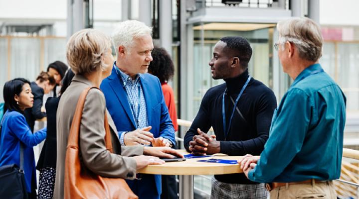 A group of business conference participants discussing a presentation in the hotel foyer together