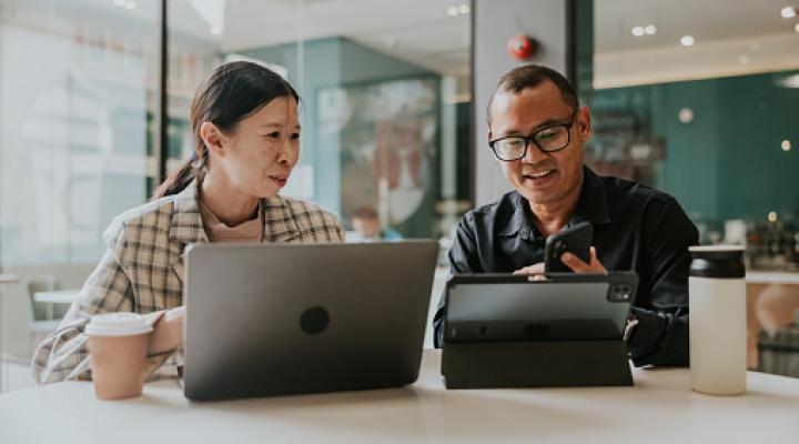 Dos personas hablando mientras usan sus computadoras portátiles