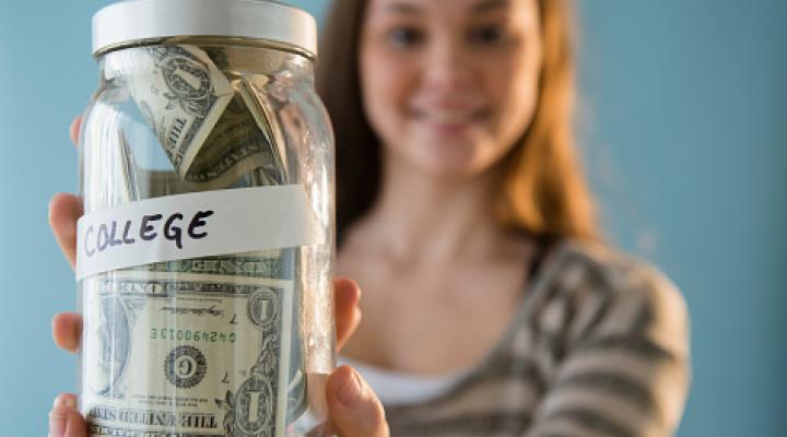 Niña hispana con un bote de ahorros para la universidad