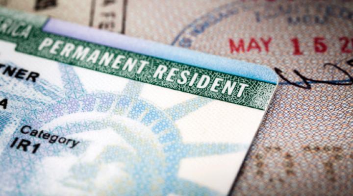 Primer plano con encuadre completo de una tarjeta de residente permanente sobre un pasaporte abierto