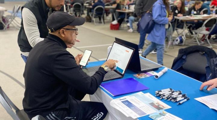 An OPA team member assists a borrower in applying for a 1% interest loan to pay for their citizenship fees at a community event.