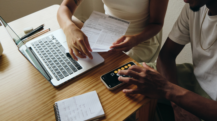 Dos personas revisan unos papeles y usan una calculadora